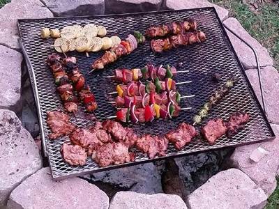 Expanded metal panel made BBQ grill is put on a circle of rocks, with meat on it roasted.