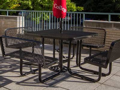 An integration of table and four chairs in use, all made from expanded metal.