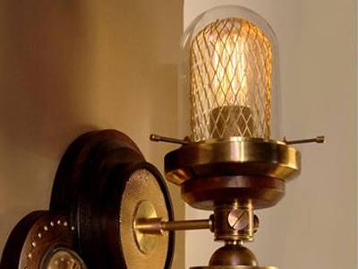 Expanded metal protects a lamp besides the wall, with glass lampshade outside.