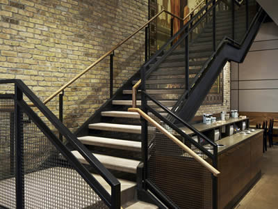Woven wire cloth stair railings with black surface and square holes in the store.