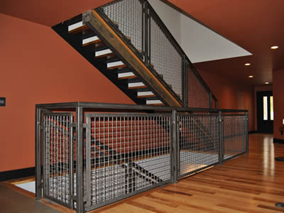 Welded wire cloth infill panels with square holes are installed on stair railings and walkway fences which are one.